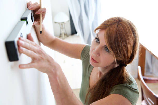 istock Mature woman marking on wall with level 967104566