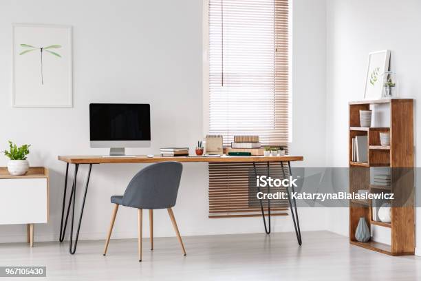 Grey Chair At Desk With Computer Monitor In Minimal Workspace Interior With Poster Real Photo Stock Photo - Download Image Now