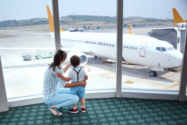 istock Mother and son with airplane on background 967108854