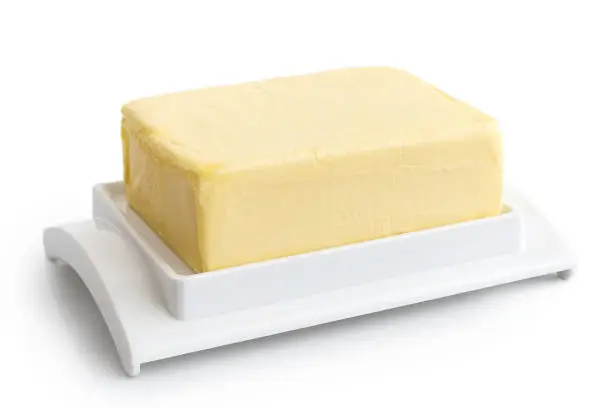 A whole block of butter on white plastic butter dish isolated on white.