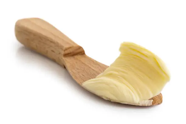 Butter spread on wooden knife isolated on white.