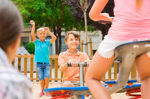 Cheerful children are teetering on the swing on the playground.