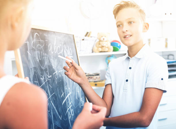 istock Boy with girl are writing on desk their homework on math 967109824