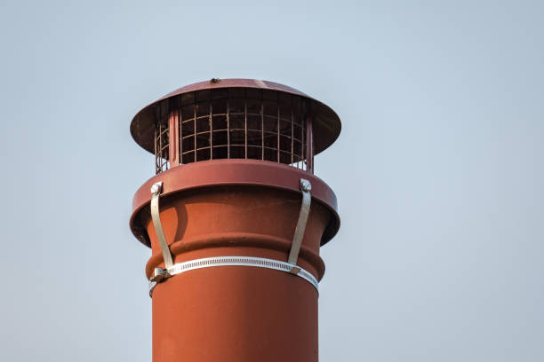 Isolated view of an old fashioned, terracotta chimney pot seen on a cottage roof, against a clear sky. stock photo