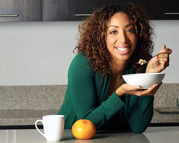 Woman eating cereal for breakfast stock photo