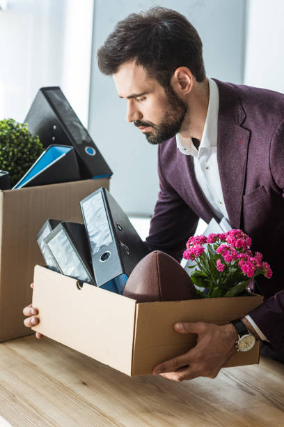 istock fired young businessman taking box of personal stuff from desk at office 967120948