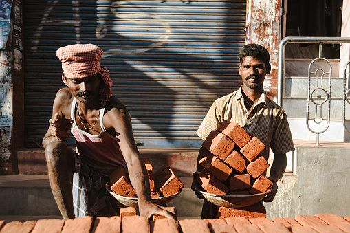 two indian workers in outdoors with plates ful of bricks, 23 february 2018 Madurai, India