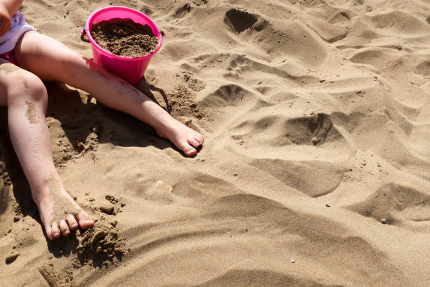 istock A child plays with a pink plastic bucket in the sand on a beach 967121532