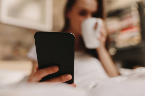istock Woman drinking bed coffee looking at mobile phone 967122138