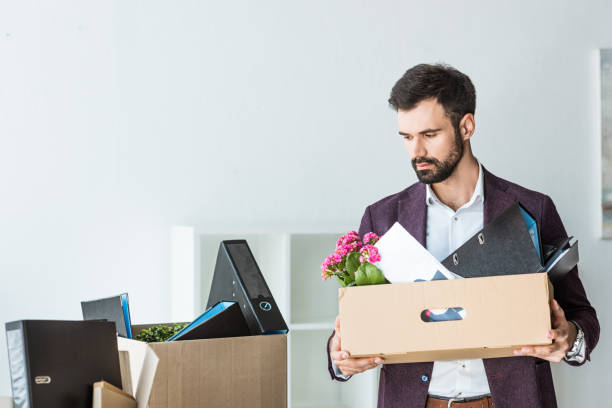 istock fired young businessman with boxes of personal stuff in office 967124464