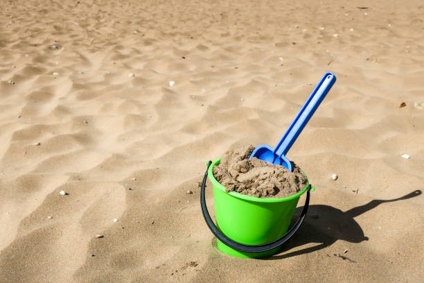 istock Green plastic bucket and blue shovel on a beach 967125264