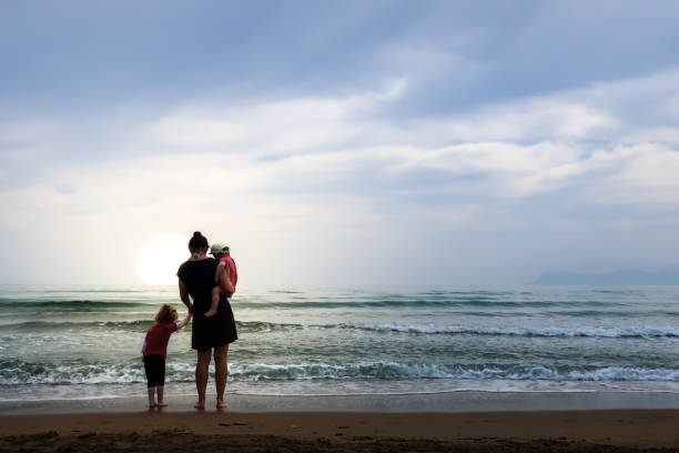istock Mom and her two daughters stand on a beach 967125874