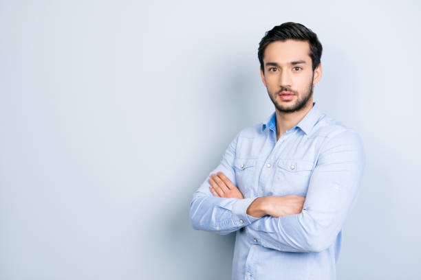 istock Portrait with copyspace empty place for advertisement of half-turned virile man with black hair holding arms crossed looking at camera isolated on grey background 967133860