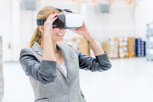 Horizontal color image of pretty manager with flying goggles at warehouse.