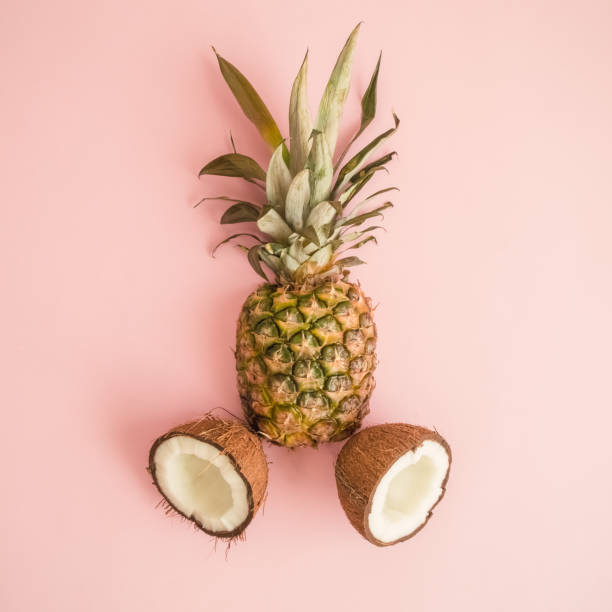 istock Flat lay of pineapple and coconut against rose background abstract. 967191154