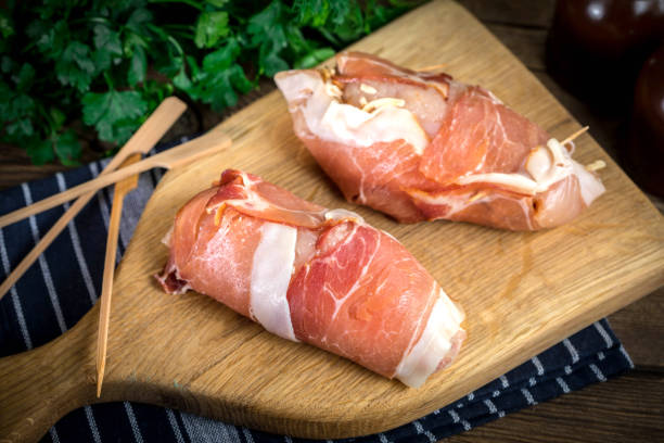 Raw chicken breast stuffed with champignon wrapped with bacon.