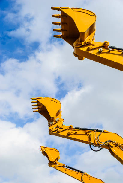 istock Buckets of three digger excavators against a blue sky 967220980
