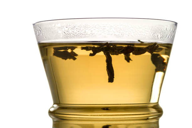 Large tea leaves are brewed in a glass beaker. Isolated on white.