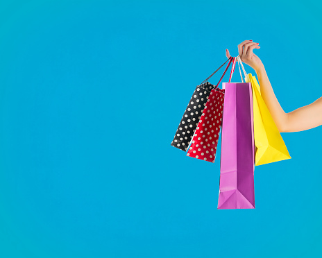 Holding fancy shopping bags on blue background