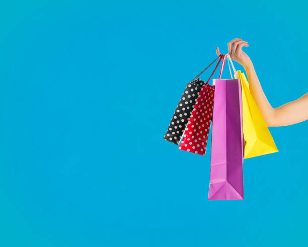 Holding fancy shopping bags on blue background stock photo