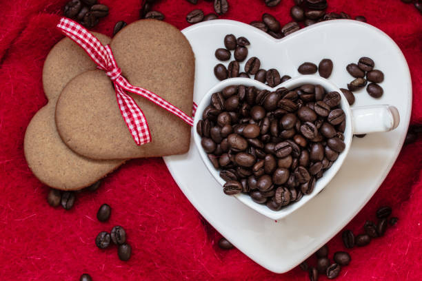 istock Coffee beans in heart shaped cup and dessert on red 967275694