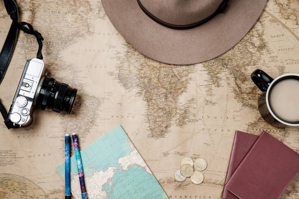 istock Flat lay adventure vintage background with hat, camera and passport on old map. Top view