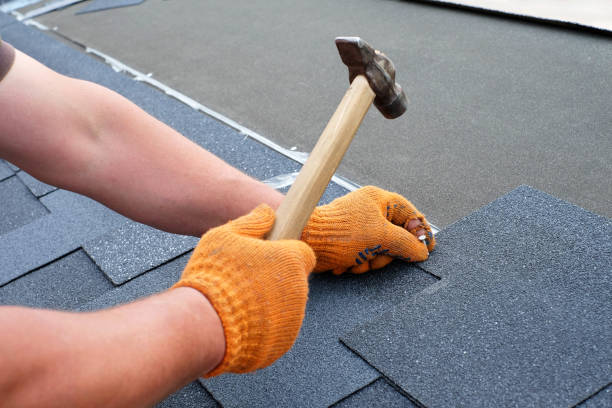 istock Roofer hands installing bitumen roof shingles using hammer in nails. 967295378