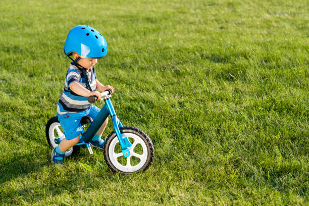 Boy in helmet riding a blue balance bike (run bike) stock photo