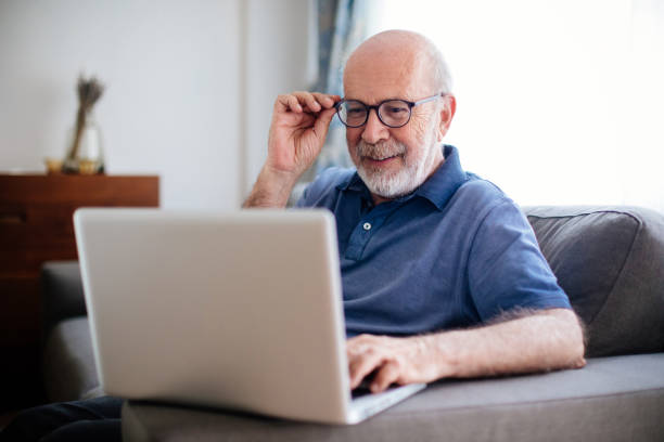 istock Senior man sitting at home using laptop wearing glasses 967329858