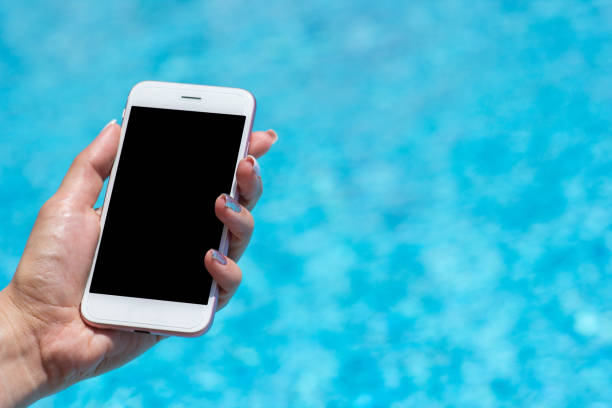 istock Woman hand using smartphone near swiming pool, close-up 967332462