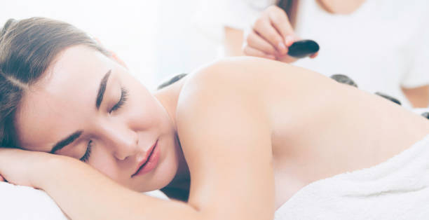 istock Hot stone massage treatment by therapist in spa. 967439186