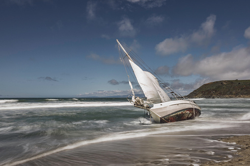 High quality stock image of a shipwrecked sailboat washed ashore in Pacifica, Ca