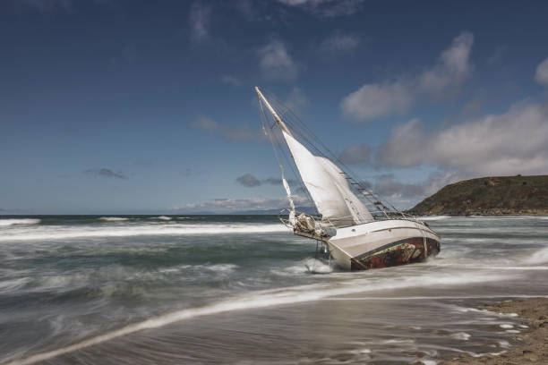 Washed Ashore Sailboat on Beach High quality stock image of a shipwrecked sailboat washed ashore in Pacifica, Ca stranded stock pictures, royalty-free photos & images