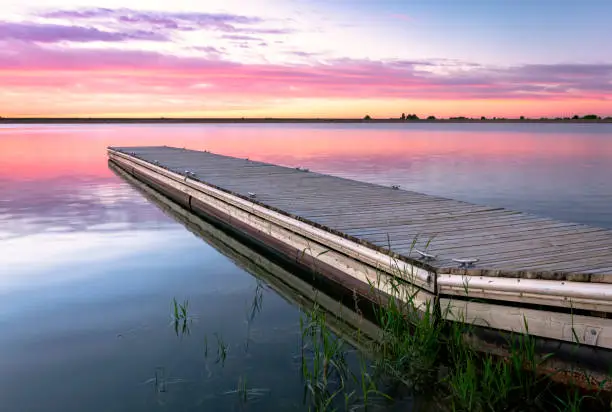 Sunrise or sunset on a fishing dock or a pier with colorful clouds reflecting in the lake located in Larimer County Colorado