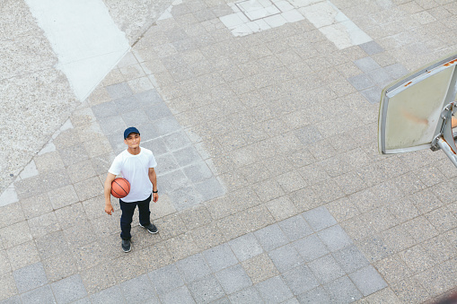 A portrait of a young Japanese man in public basketball court.