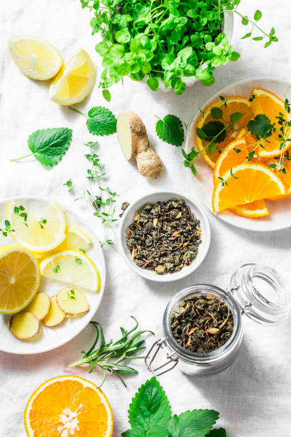 istock Ingredients for making cold aromatic green tea - dry green tea, lemon, orange, ginger, mint, rosemary on a light background, top view. Flat lay 967509130