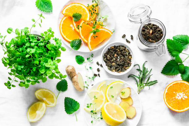 Ingredients for making cold aromatic green tea - dry green tea, lemon, orange, ginger, mint, rosemary on a light background, top view. Flat lay