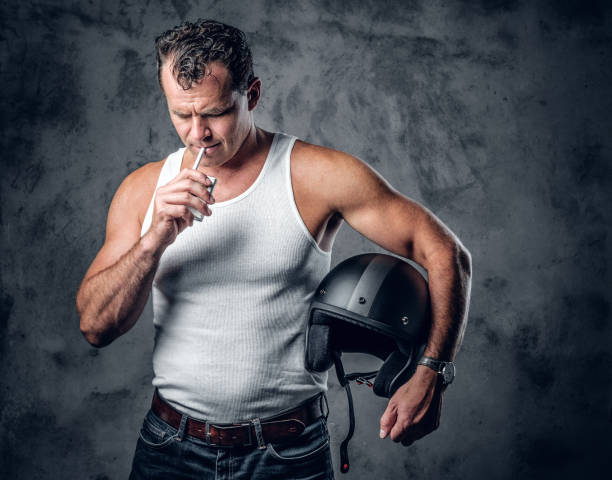 istock A man smoking cigarette and holds a motorcycle helmet. 967577518