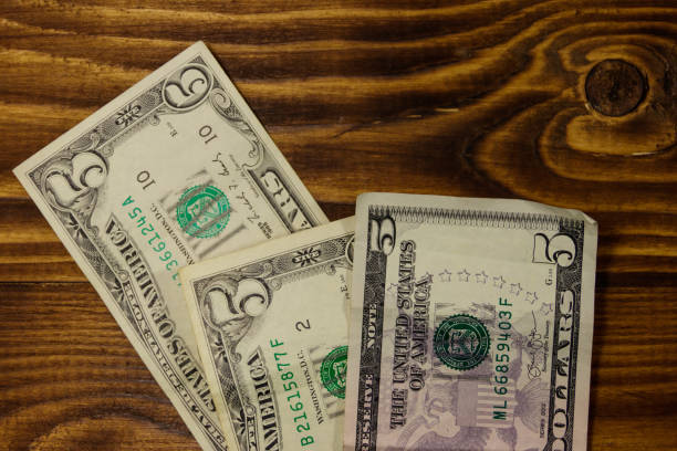 istock Five dollars banknotes on wooden background. Top view 967587232