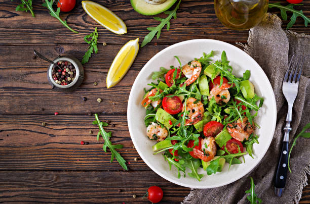 insalatiera fresca con gamberi, pomodoro, avocado e rucola su sfondo di legno da vicino. cibo sano. mangiare pulito. vista dall'alto. lay piatto. - pepper vegetable red green foto e immagini stock