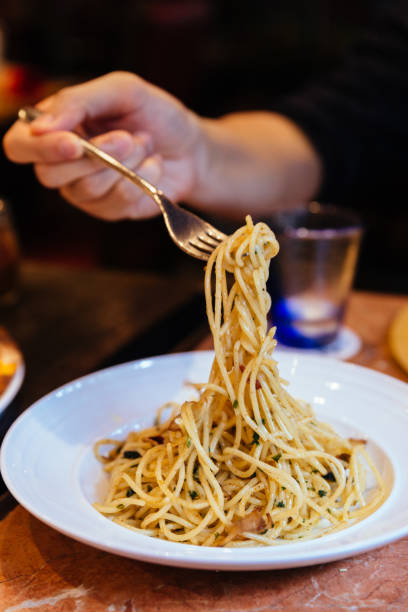 istock Mushroom and Garlic Spaghetti with a fork held by a hand. 967590614