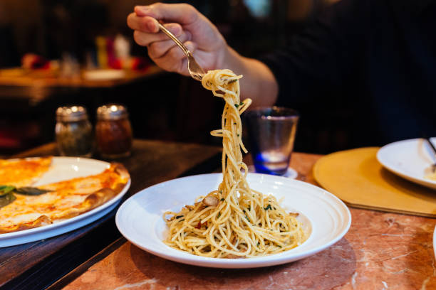 istock Mushroom and Garlic Spaghetti with a fork held by a hand. 967590748