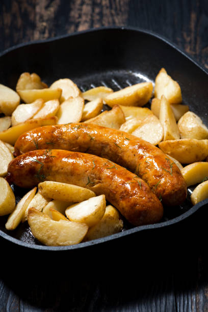istock fried pork sausages with potatoes in frying pan, vertical 967590870