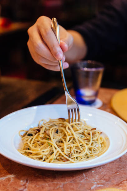 istock Mushroom and Garlic Spaghetti with a fork held by a hand. 967593080