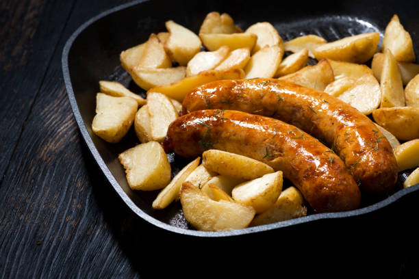 istock fried pork sausages with potatoes in frying pan 967594188