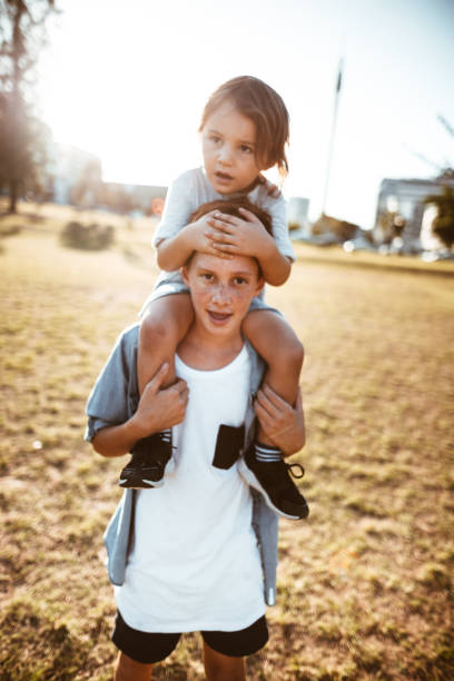 istock two lovely kids piggyback at the park 967611182