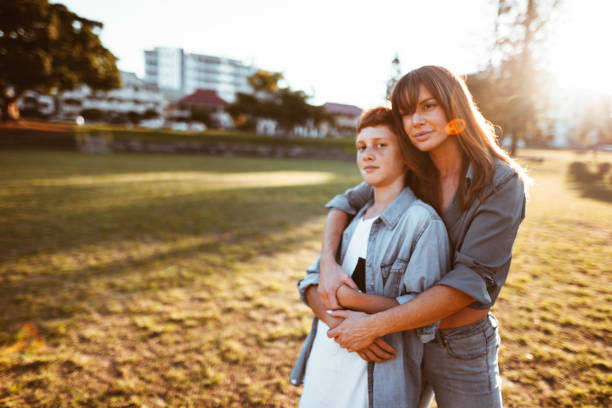 istock mom with arm around the son in the park 967626844
