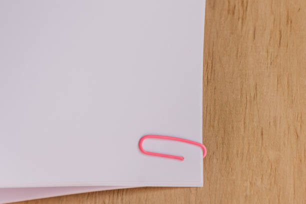 Blank paper clipped on wooden desk background.