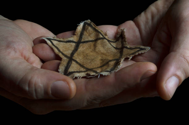 Jewish badge in the hands of a man Closeup of a ragged Jewish badge in the hands of a man holocaust stock pictures, royalty-free photos & images