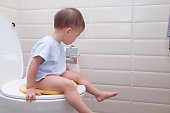 かわいい小さなアジア 2 歳幼児赤ちゃん男の子の子供の子供の浴室のアクセサリとトイレのモダンなスタイルの上に座って